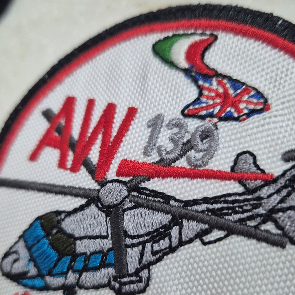 Embroidered patch with helicopter design, 'AW139' text, and Italian and British flags on a white background.